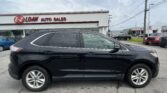 Black SUV in the foreground at a car dealership lot, with an E-Z Loan Auto Sales sign on a white building in the background.
