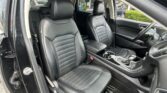 Interior of a car showing black leather front seats, center console, and steering wheel, viewed from the driver’s side doorway.