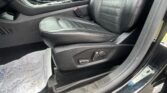 Black leather car interior showing the front passenger seat, center console, and visible seat belt buckle near the seat.