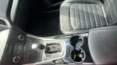 Interior of a car shows the center console with a leather-wrapped gear shifter, cup holders, and climate control buttons beside it.