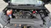 Front view of a car with the hood raised, exposing the engine bay and coolant reservoir on the left edge