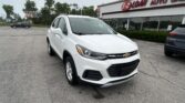 White Chevrolet SUV parked diagonally in a dealership lot in front of an EZ Loan Auto Sales building sign.