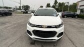Front view of a white Chevrolet SUV in a parking lot with other cars and dealership buildings in the background