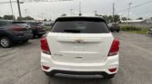 Rear view of a white Chevrolet Trax SUV in a parking lot with other cars nearby.