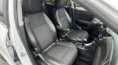 Front interior of a car with black leather seats and orange stitching; driver’s door is open and the center console is visible.