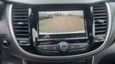 Car rearview camera display with orange guiding lines over a parking lot scene