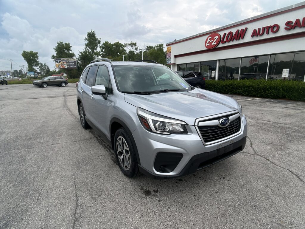 Silver SUV parked in front of a car dealership with 'E-Z LOAN AUTO' sign on the building.