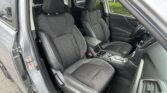 Open-driver-side-view of a car interior with two black fabric front seats, center console, and steering wheel visible from the door frame.