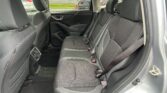 Interior of a car's rear seating area with black fabric seats, three headrests, and visible seat belts.