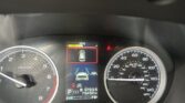 Close-up of a car dashboard showing the tachometer on the left, speedometer on the right, and a central digital display with vehicle icons and fuel/economy indicators.
