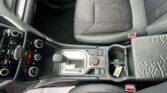 Interior of a car: driver seat with gray patterned upholstery, center console with gear selector and climate controls, and cup holder nearby