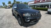Black Jeep SUV in a dealership lot with a white building and red E-Z LOAN AUTO SALES sign.