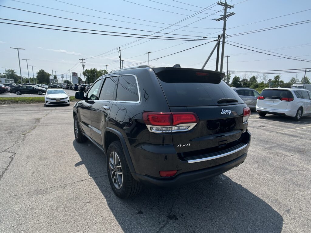 Rear of a black Jeep SUV in a crowded parking lot with power lines overhead and other cars in the background.