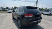 Rear of a black Jeep SUV in a crowded parking lot with power lines overhead and other cars in the background.