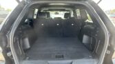 Open SUV rear hatch showing spacious cargo area with third-row seats upright and headrests visible behind the folded tonneau panel and back seats.