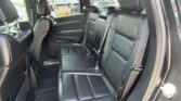 Rear row of black leather seats in an SUV, with three seat positions and visible seat belts.