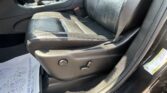 Interior of a black leather car seat and center console with gear shifter, seat belt, and controls visible on the side panel.