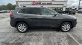 Gray Jeep Cherokee SUV parked in a dealership lot with E-Z Loan Auto Sales building in the background