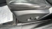 Close-up of a black car seat edge with stitching and seat adjustment levers visible on the lower side panel.
