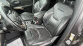 Interior view of a black leather Jeep with driver and front passenger seats and center console visible