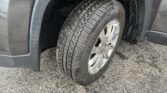 Front vehicle tire mounted on a silver alloy wheel, exposed wheel well and fender in view.