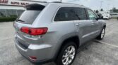 Rear and side view of a silver SUV with roof rails parked in a car dealership lot.