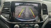 In-car display showing the rearview camera view with parking lot behind and green-yellow-red guide lines in the screen.