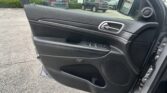 Interior of a car door panel with a chrome door handle, control buttons, and speaker, seen from the passenger seat.
