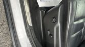 Open car door interior with a black leather seat and a white promo bag hanging over the seat, showing printed text and footprints.