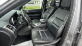 Interior of a black leather SUV with steering wheel, center console, and front seats; driver-side door open to the outside street view.
