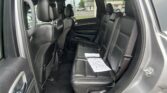 Rear cabin of a black SUV with leather seats; papers rest on the rear seat near the belt buckle area, window view outside visible.