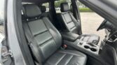 Black leather SUV interior with front captain seats and a center console, steering wheel on the right side, and cup holders visible between the seats.