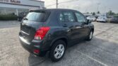 Dark gray SUV parked in a car dealership lot with an 'AUTO SALES' sign visible in the background