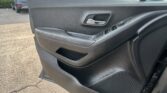 Close-up of a car interior door panel with a chrome door handle and window control buttons
