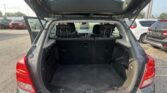 SUV with rear hatch open, showing a large empty cargo area and folded back seats in a parking lot.