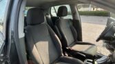 Interior view of a car's front seats and dashboard with door open, showing the steering wheel on the right and a parking lot outside.