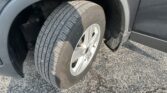 Close-up of a vehicle tire mounted on a silver wheel inside a black wheel well, showing tread details and fender edge.