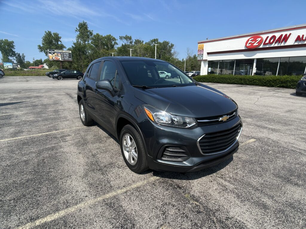 Dark gray Chevrolet SUV parked in a sunny lot with an EZ Auto storefront in the background.