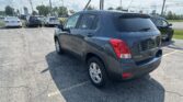 Rear three-quarter view of a dark blue Chevrolet Trax SUV parked in a car lot, with other cars and a Toyota dealership sign visible in the background.