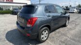 Blue SUV parked in a car dealership lot near a building with a red 'AUTO SALES' sign.