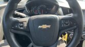 Steering wheel inside a Chevrolet, dashboard gauges visible and control stalks on both sides, daylight through the windshield.