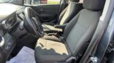 Interior of a car focusing on the driver and front passenger seats, steering wheel, and center console in a dealership parking lot view outside the window.