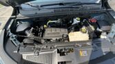 Open car hood exposing the engine bay, including the battery, coolant reservoir, and various hoses and components