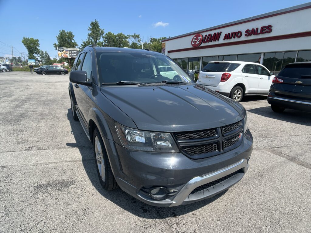 Gray SUV in the foreground at an auto dealership lot with other cars and the E-Z Loan Auto Sales building in the background.