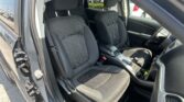Front seats of a dark car interior with patterned fabric and headrests, rear seats visible through the cabin open door