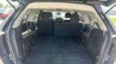 Open SUV trunk showing cargo area with third-row seats upright and vehicle exterior visible at street-side parking lot
