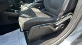 Front passenger seat and center console of a car, with the gear shifter and seat belt visible in daylight interior lighting.