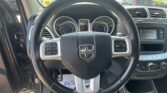 View from driver seat showing steering wheel and dashboard with parked cars outside in a lot nearby.