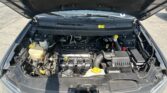 Open hood view of a car engine bay with various hoses, the battery, and a coolant reservoir visible on the left side.