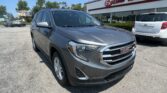 Gray GMC SUV in foreground at a car dealership lot with EZ Loan Auto Sales sign on the building in the background.